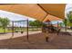 Community playground featuring swings, slides, climbing structures, and a yellow spring rider in a sand area at 41444 W Capistrano Dr, Maricopa, AZ 85138
