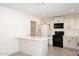 Modern kitchen with white cabinets, a breakfast bar, black appliances, and light wood tile flooring at 4902 E Charter Oak Rd, Scottsdale, AZ 85254