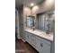 Bathroom featuring double sinks, white cabinetry, and a large framed mirror at 5633 N 205Th Ln, Buckeye, AZ 85396