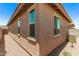 Backyard exterior displaying tan stucco walls, brown tile roof, and gravel landscaping surrounding the home at 5641 N 205Th Ln, Buckeye, AZ 85396