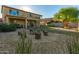 Inviting backyard featuring a custom fire pit, seating logs, green grass, covered patio and a play structure at 6506 W Bent Tree Dr, Phoenix, AZ 85083