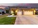 Beautiful home exterior featuring a well-manicured lawn, stone accents, and a three-car garage at dusk at 69 E Benrich Dr, Gilbert, AZ 85295