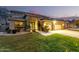 Charming home exterior with well-manicured lawn, warm lighting, and a three car garage at 69 E Benrich Dr, Gilbert, AZ 85295