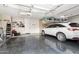 Spacious garage featuring a glossy floor, storage shelving, overhead racks, and a modern white SUV at 69 E Benrich Dr, Gilbert, AZ 85295