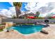 Sparkling pool with a stone waterfall feature, ample seating, and lush landscaping on a sunny day at 69 E Benrich Dr, Gilbert, AZ 85295