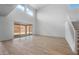 A bright living room with large sliding glass doors, a high ceiling, and hardwood-style flooring and a staircase at 6980 W Hedge Hog Pl, Peoria, AZ 85383