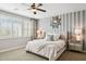 Stylish bedroom with neutral carpet, fan, a striped accent wall, and charming decor, creating a serene atmosphere at 937 W Glacier Dr, Chandler, AZ 85248