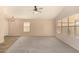 Spacious living room featuring neutral carpeting, a ceiling fan, and natural light from the windows at 9715 E Osage Ave, Mesa, AZ 85212
