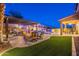 Luxurious backyard featuring a fire pit, an outdoor kitchen, a pool with water features, and lush artificial turf at 10038 W Redbird Rd, Peoria, AZ 85383