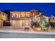 Stunning two-story home featuring an attached garage, balcony, and beautifully landscaped front yard at twilight at 10038 W Redbird Rd, Peoria, AZ 85383