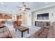 Open-concept living room and kitchen with tile flooring, ceiling fan, and media center at 10038 W Redbird Rd, Peoria, AZ 85383