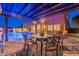 Outdoor dining space with poolside view, built in grill, desert landscaping, and lighting at 10038 W Redbird Rd, Peoria, AZ 85383