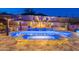 Lush backyard with a sparkling pool, spa, and multi-tiered landscaping complemented with vibrant uplighting at 10038 W Redbird Rd, Peoria, AZ 85383