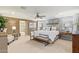 Spacious main bedroom featuring a large bed, neutral tones, ceiling fan, and an ensuite bathroom at 11544 W Ashby Dr, Peoria, AZ 85383