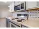 Close-up of electric range with stainless-steel microwave and neutral countertops at 13275 W Bolero Dr, Sun City West, AZ 85375