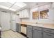 Galley-style kitchen with white cabinetry, gray lower cabinets, and stainless-steel sink at 13275 W Bolero Dr, Sun City West, AZ 85375