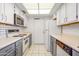 Well-lit kitchen with stainless-steel microwave, white cabinets, and tile flooring at 13275 W Bolero Dr, Sun City West, AZ 85375