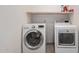 Laundry room equipped with front load washer/dryer and overhead shelving for storage at 1449 W Commerce Ave, Gilbert, AZ 85233