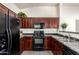 Bright kitchen features sleek black appliances, dark wood cabinets and a black countertop for a modern appeal at 2024 S Baldwin St # 161, Mesa, AZ 85209