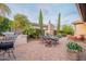 Spacious backyard offers outdoor dining, built-in grill, lush landscaping, and water feature at 37148 N Stoneware Dr, Queen Creek, AZ 85140