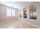 Empty room with beige walls, tile floor, shutters, and arched doorways perfect to customize to your taste at 37148 N Stoneware Dr, Queen Creek, AZ 85140