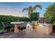Outdoor kitchen offers a bar, grill, and lush landscaping with chairs for casual dining at 37148 N Stoneware Dr, Queen Creek, AZ 85140