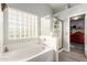 Bright bathroom showcases a soaking tub, glass-enclosed shower, and tile flooring with natural light at 3848 S Coach House Dr, Gilbert, AZ 85297
