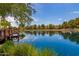 Scenic community lake with lush green trees, serene blue water and a view of neighborhood homes at 3848 S Coach House Dr, Gilbert, AZ 85297