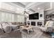 Bright living room with a tray ceiling, a ceiling fan, and a stone fireplace, furnished with a large sectional sofa at 4167 E Sierra Madre Ave, Gilbert, AZ 85296