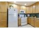 Well-lit kitchen featuring wood cabinets, white appliances, and granite countertops at 4202 E Broadway Rd # 126, Mesa, AZ 85206