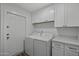 Well-lit laundry room with ample cabinet space and side-by-side washer and dryer at 4228 N 87Th St, Scottsdale, AZ 85251