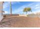 Large, dirt backyard featuring a block wall and mature trees against a blue sky backdrop at 4234 S 62Nd Ln, Phoenix, AZ 85043