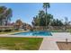 Community pool with clear blue water, lush landscaping, and sunny skies in a fenced area at 439 N Cobblestone St, Gilbert, AZ 85234