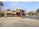 Stunning exterior of a tan home featuring multiple car garage, mature trees and front flower garden at 4446 E Camelback Rd # 104, Phoenix, AZ 85018