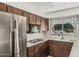 Kitchen featuring stainless steel refrigerator, wood cabinetry, and natural light from the window at 4728 N 61St Ave, Phoenix, AZ 85033
