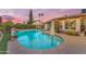 Tranquil backyard pool with rock feature, mature landscaping, and a serene ambiance at sunset at 6126 W Sweetwater Ave, Glendale, AZ 85304