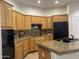 Well-lit kitchen with light wood cabinets, granite countertops, and black appliances at 7318 E Woodsage Ln, Scottsdale, AZ 85258