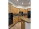 Well-lit kitchen featuring light wood cabinets, granite countertops, and black appliances at 7318 E Woodsage Ln, Scottsdale, AZ 85258
