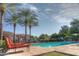 Community pool area with clear blue water, surrounded by comfortable lounge chairs and mature palm trees at 7318 E Woodsage Ln, Scottsdale, AZ 85258