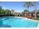 Community pool area with clear blue water, surrounded by comfortable lounge chairs and mature palm trees at 7318 E Woodsage Ln, Scottsdale, AZ 85258