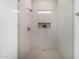 Tiled walk in shower with black fixtures, a small window, and plant shelf at 7325 E Virginia Ave, Scottsdale, AZ 85257