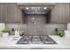 Close-up of modern gas cooktop and range hood with tile backsplash and pot filler faucet at 7325 E Virginia Ave, Scottsdale, AZ 85257