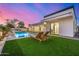 Stunning backyard featuring a modern pool, waterfall feature, outdoor kitchen, and pristine artificial grass at 7325 E Virginia Ave, Scottsdale, AZ 85257
