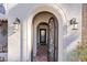 Stunning arched entry way with wrought iron door, stone accents, and stylish outdoor lighting at 8719 E San Marcos Dr, Scottsdale, AZ 85258