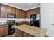 Kitchen featuring a island, black appliances, brown cabinets and granite countertops at 10132 E Isleta Ave, Mesa, AZ 85209