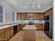 Open kitchen with brown cabinets, granite countertops, island, tile floors, and black appliances at 10132 E Isleta Ave, Mesa, AZ 85209