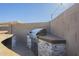 An outdoor kitchen features a stainless steel grill, granite counters, and stone accents at 10251 W Gambit Trl, Peoria, AZ 85383