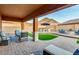A luxurious covered patio offers seating, a bar, artificial grass, and a fire pit, perfect for entertaining at 10251 W Gambit Trl, Peoria, AZ 85383
