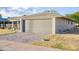 View of the two-car attached garage with brick-paved driveway, and low-maintenance landscaping at 10326 W Kingswood Cir, Sun City, AZ 85351