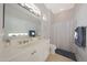 Bright bathroom with a large mirror, white cabinets, and a shower featuring patterned wallpaper at 12950 W Quinto Dr, Sun City West, AZ 85375
